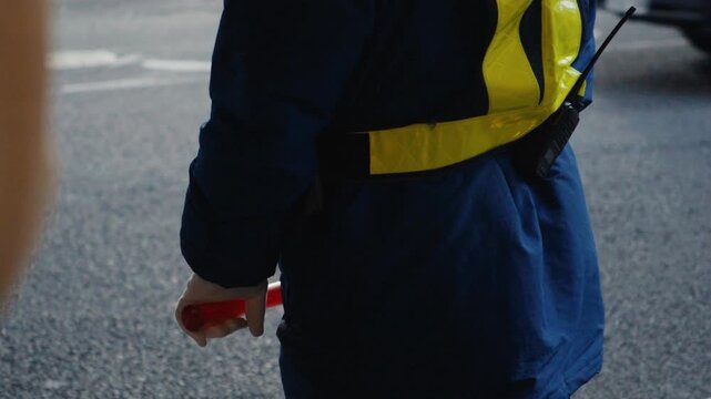 Security guard directing traffic with red light baton
