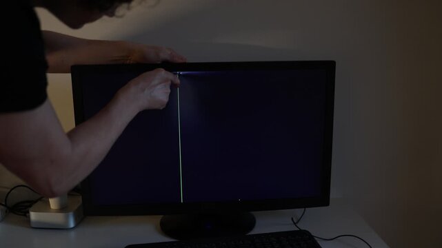 Home office worker frustrated while trying to repair damaged computer monitor modern technology failure electronic troubleshooting cinematic indoor repair atmosphere
