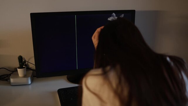 Girl sitting in front of malfunctioning computer with dark striped display frustrated work from home atmosphere modern digital lifestyle problem cinematic scene