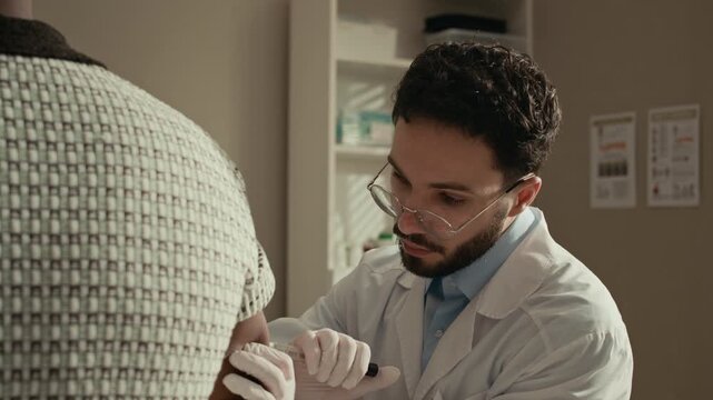 Medium closeup of Middle Eastern doctor showing insulin injection procedure to unrecognizable male patient during diabetes care visit