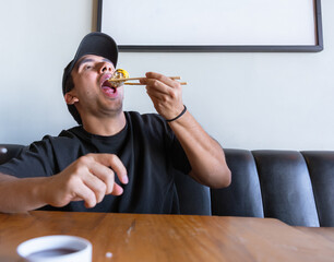 Man enjoying sushi roll with chopsticks at restaurant © Fabian Vargas