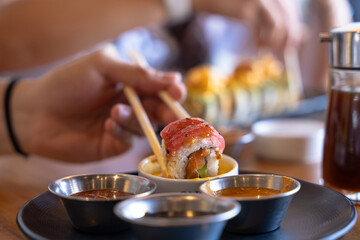 Person enjoying tuna salmon sushi roll with chopsticks © Fabian Vargas