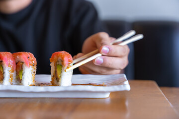 Person eating sushi roll with chopsticks at restaurant © Fabian Vargas