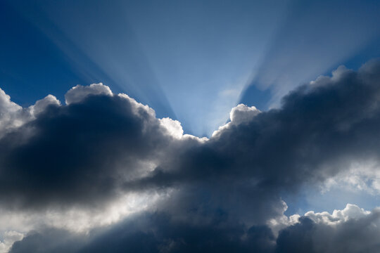 Aerial view of bright sunbeams breaking through dark storm clouds against a blue sky in Klobouky u Brna, Jihomoravsky kraj, Czechia.