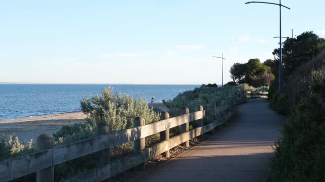 Scenic coastal walking path and wooden fence at Werribee South near a beach overlooking Port Phillip Bay at sunset; peaceful outdoor recreation trail in Melbourne, Victoria, Australia.