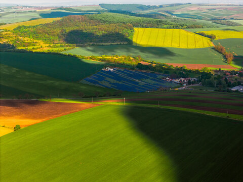 Aerial view of the FVE Bohumilice solar power plant nestled among rolling green hills and agricultural fields with dramatic cloud shadows Klobouky u Brna, Jihomoravsky kraj, Czechia.