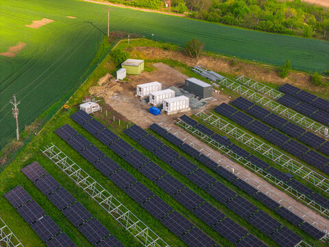 Aerial view of FVE Bohumilice solar power plant with rows of photovoltaic panels and storage containers surrounded by fields Klobouky u Brna, Jihomoravsky kraj, Czechia.