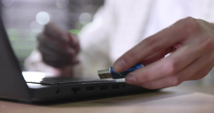 Woman inserting flash drive into laptop at wooden table indoors, selective focus