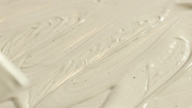 Woman smearing natural clay paste for facial and body care with makeup brush, closeup. Mud therapy