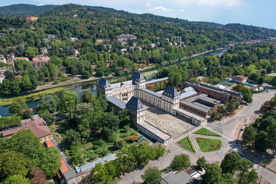 Aerial view of Castello del Valentino with its grand courtyard and historic architecture along the Po River and lush green hills in the background in Torino, Piemonte, Italy.