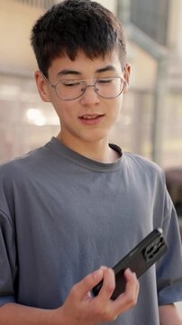 Young man reacting with frustration while looking at smartphone outdoors. Vertical video of candid people, authentic emotions, stress, negative news and communication concept.