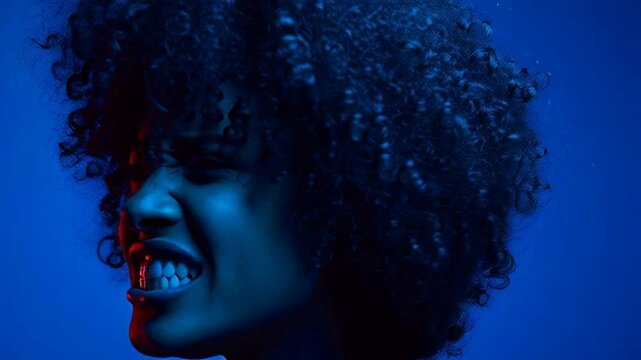 Close-up of a woman with an afro screaming in dramatic blue and red lighting.