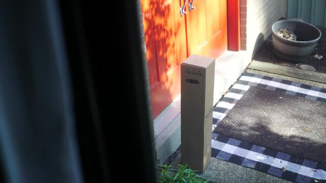 A Tall Narrow Cardboard Package Sitting Outside Residential Home