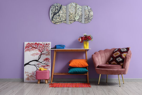 Interior of stylish living room with pink armchair, table, painting and mirror