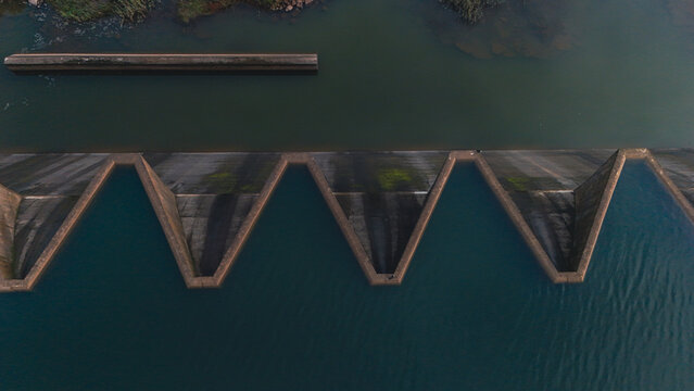 Aerial view of the geometric zigzag pattern of a dam labyrinth spillway with dark water Mooi River, KwaZulu-Natal, South Africa.