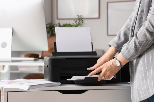 Businesswoman using modern printer in office