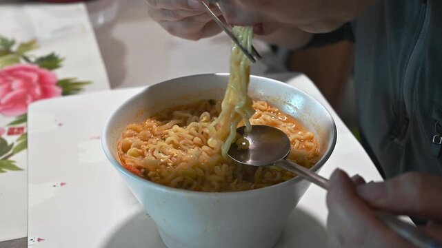 close up of a man eating delicious korean instant noodles, slurping ramen with chopsticks and spoon