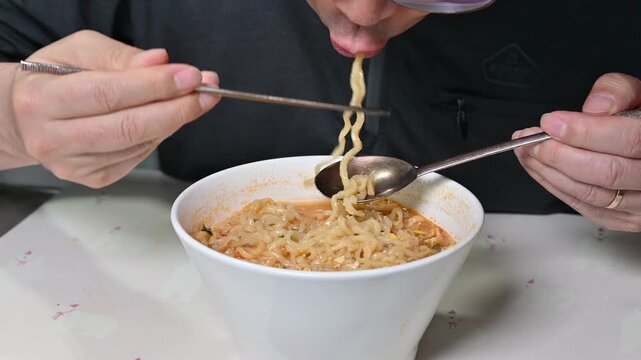 close up of a man eating delicious korean instant noodles, slurping ramen with chopsticks and spoon