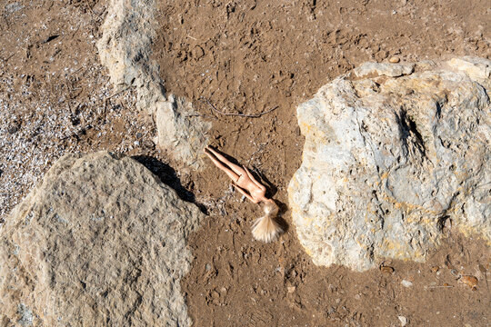 A broken doll lying on a sandy beach, symbolizing environmental pollution and the consequences of overconsumption. Perfect for themes of ecological crisis, plastic pollution, human impact on nature