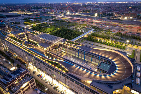 Aerial view of the historic Lingotto building featuring the iconic rooftop test track illuminated at twilight in Turin, Piedmont, Italy.
