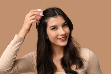Fototapeta premium Beautiful young woman brushing her hair on brown background