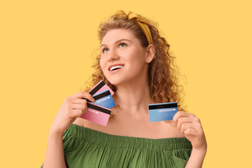 Naklejka premium Beautiful young woman with credit cards on yellow background