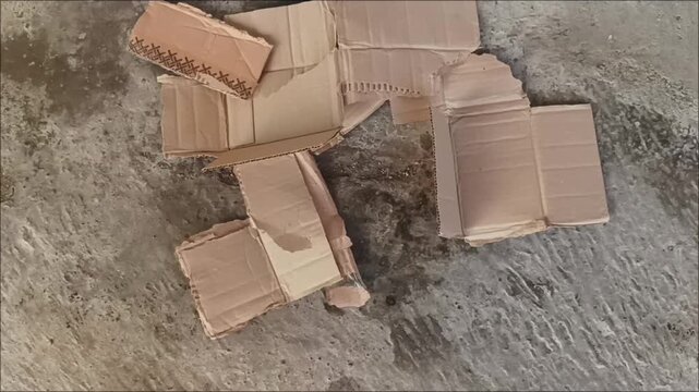 Top view of scattered wet corrugated cardboard sheets on a textured cement ground