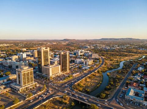 Aerial view of Gaborone, Botswana's capital city, showcasing modern skyscrapers and urban development along a highway.