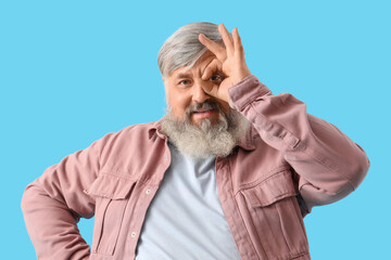 Fototapeta premium Mature bearded man showing OK on blue background