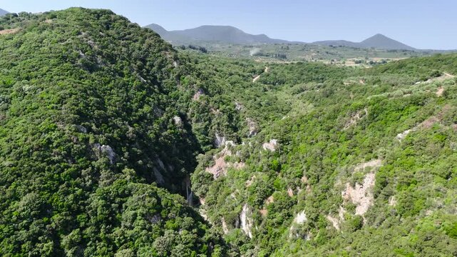 Aerial Drone View of Polylimnio Canyon in Peloponnese, Greece, with Green Mountain Gorge, Rocky Cliffs, Hidden Waterfall and Mediterranean Landscape