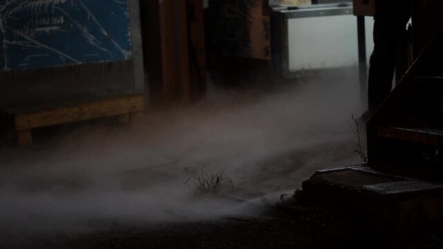 Smoke slowly rolls out of a building at night.