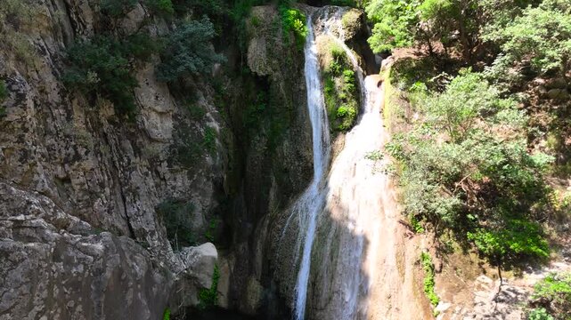 Close Aerial View of Polylimnio Waterfall Cascading into Natural Pool in Rocky Canyon, Peloponnese Greece