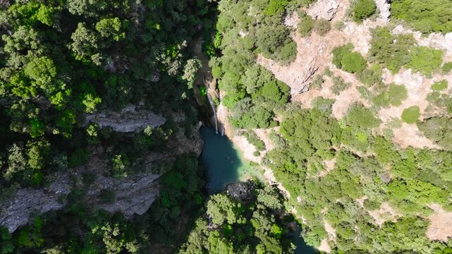 Aerial View of Swimmers in Natural Pool Below Polylimnio Waterfall in Rocky Green Canyon, Peloponnese Greece