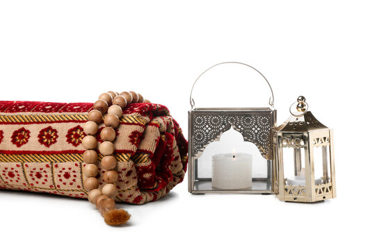 Muslim lamps with prayer beads and mat on white background