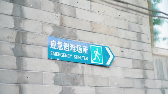 Emergency shelter sign on the wall in Beijing with bilingual text, indicating safety direction and public infrastructure for disaster preparedness in the urban environment.