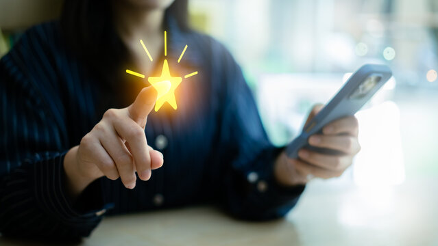 Loyalty rewards and redeem points concept with smartphone app. Close up of woman using mobile phone with glowing star icon for customer privilege, membership bonus, and marketing promotion program