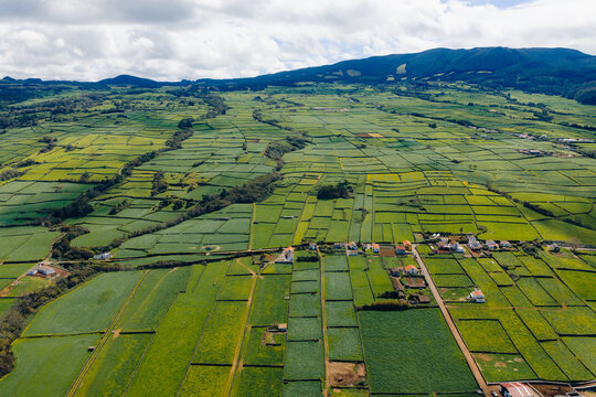Aerial view of the lush green patchwork fields and stone walls of Terceira Island under a cloudy sky in Azores, Portugal.