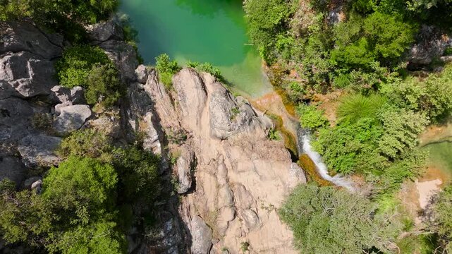 Top Down Drone View of Polylimnio Natural Pools, Small Waterfall and Swimmers in Green Forest Canyon, Messinia, Greece