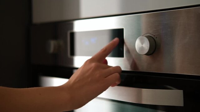 Side view of the woman turning on the electrical oven in the kitchen to baking dessert. Checking readiness of the food. 