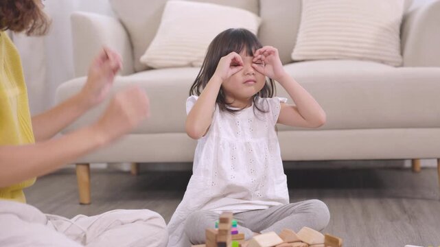 mother, daughter, family, Asian little girl touching ear with curious thinking expression at home, childhood learning moment, emotional quotient development, parenting lifestyle, cognitive behavior