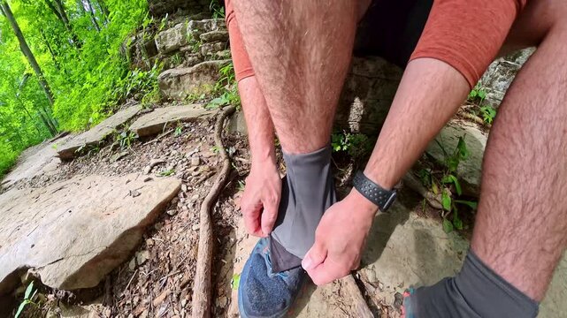 Retying Shoelace and Adjusting Gaiter on Rock in Forest