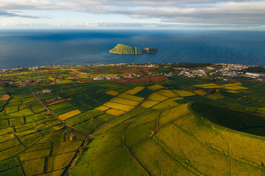 Aerial view of Pico Dona Joana geodesico overlooking the lush green patchwork fields and the Atlantic coastline in Feteira, Acores, Portugal.