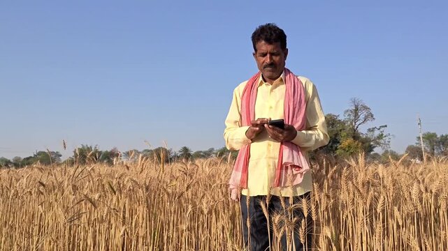 Happy indian farmer using mobile phone in field