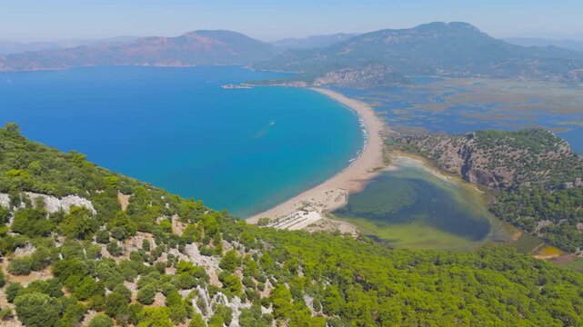 Dalyan, Turkey. Iztuzu Beach and Dalyan River delta, aerial drone view of turquoise Mediterranean waters, golden sand spit, and green mountains on a sunny summer day. Aerial View