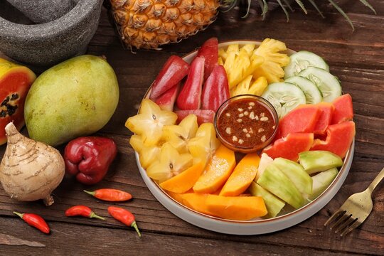 rujak buah served with mixed fresh fruits, palm sugar sauce, peanuts, and chili seasoning.
