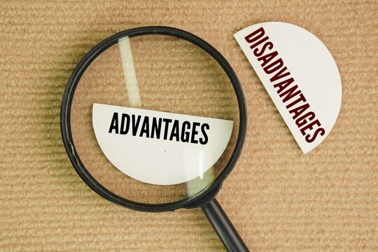 A magnifying glass and paper with the words Advantages and Disadvantages. Advantages are beneficial factors that provide a better position, while disadvantages are drawbacks that hinder progress