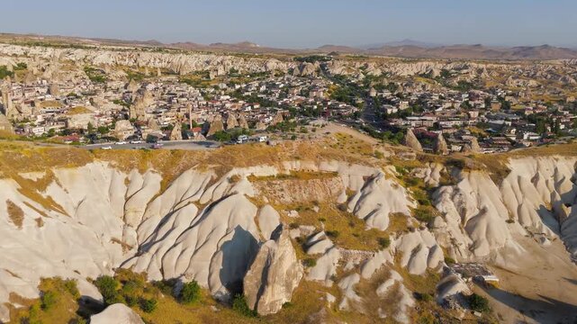 Goreme, Nevsehir, Turkey. Panoramic aerial view over the town and surrounding Cappadocia valley, fairy chimneys and eroded rock formations rising among cave dwellings under clear morning light. Aeria