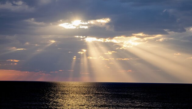 Majestic sunrays pierce through dramatic cloud formations, casting a golden, ethereal glow across the vast, tranquil ocean surface during a breathtaking sunrise or sunset moment