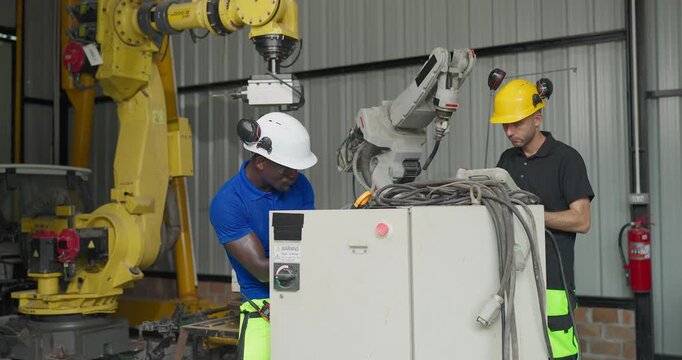 Technicians troubleshoot a robotic arm control system in a workshop, checking settings, electrical components and maintenance data for automation upgrade.

