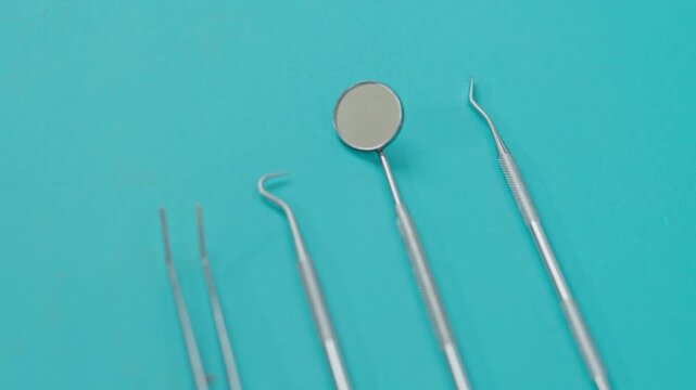 Close-Up Rack Focus Of Stainless Steel Dental Instruments Arranged Neatly On Blue Background